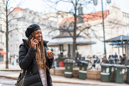 Woman on the phone eating pastel de nata in Lisbon, Portugal