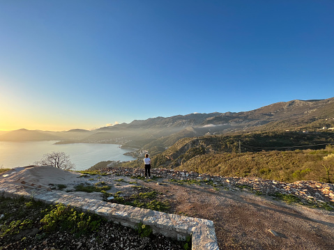 Woman stands on top of a mountain and looks at the Kotor Bay. Back view. High quality photo