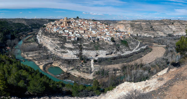 Panoramic view of the town of Jorquera in the province of Albacete, Spain. panoramic view of a village surrounded by a river with a blue sky with little cloud cover. paisaje urbano stock pictures, royalty-free photos & images