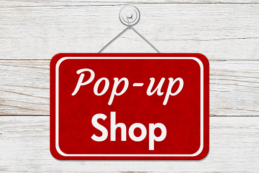 Pop-up Shop message on a red sign on weather wood wall