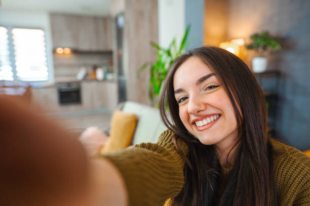istock Smiling young woman taking selfies while relaxing at home 1471725681