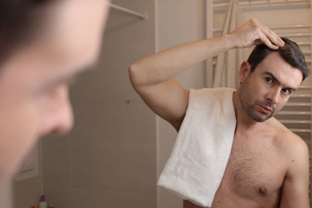 Man observing his hairline in the mirror stock photo