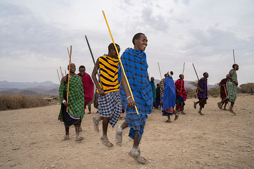Karatu, Tanzania - October 16th, 2022: A group of masai men in traditional outfits, dancing during a show for tourists near their village.