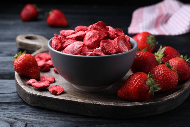 gefriergetrocknete und frische erdbeeren auf schwarzem holztisch, nahaufnahme - dry strawberry dried food fruit stock-fotos und bilder