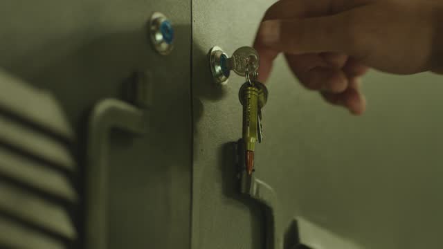 4k Close up view of green colored metallic military Locker Room . Soldier putting bag inside safe and locking door . Military dressing room , storage . Swat or elite unit training concept .