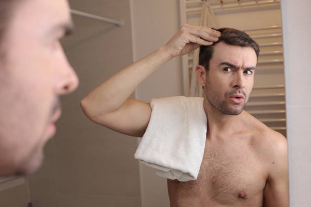 istock Man observing his hairline in the mirror 1471733336