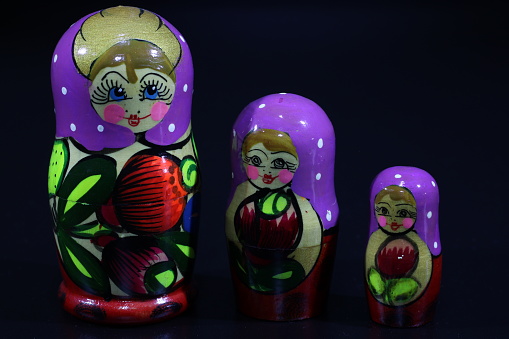 This photo showcases three Matryoshka dolls in traditional folk art style, symbolizing the iconic Russian nesting dolls. The largest doll is on the bottom, with the two smaller ones nestled inside, each painted with intricate and colorful designs. The dolls are displayed against a plain background, emphasizing their unique characteristics and traditional craftsmanship. The photo evokes the charm and cultural richness of Russia, making it a great visual representation of its heritage and art.