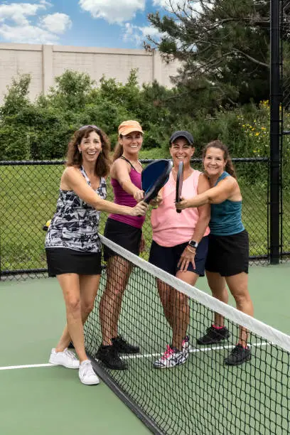 Photo of Four Female Pickleball Players Touch Paddles