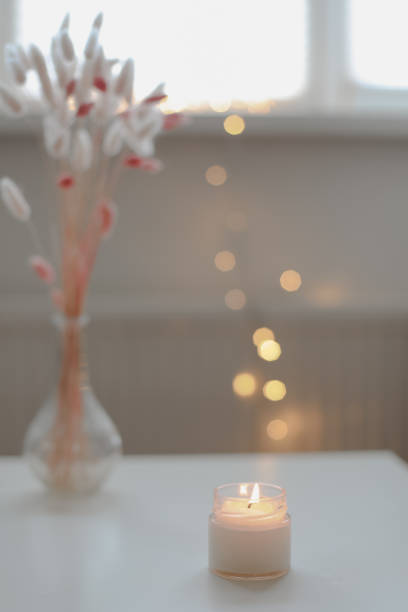 istock Cozy home interior decor, burning candle on table against blurred lights. Handmade scented soy wax candle in a glass. space for text. 1471735757