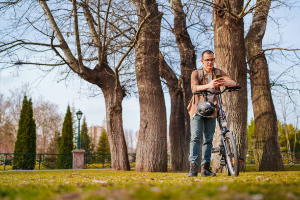 Young man using mobile phone with his bike, outdoors.