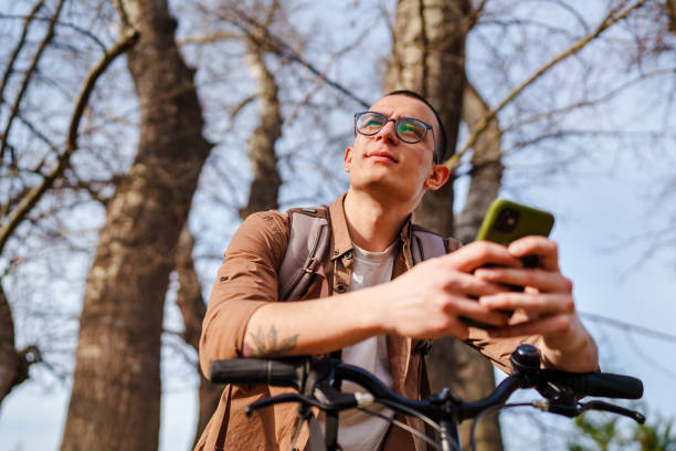 istock Young man using mobile phone with his bike, outdoors. 1471739336