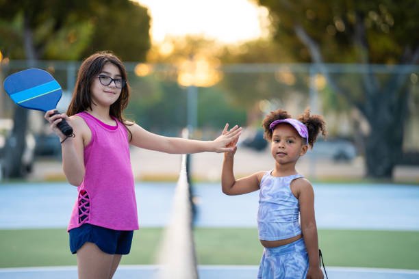 Best friends high giving a high five  by a pickle ball net