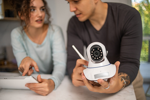 A young couple installs a security camera in their new home, an alarm system, they plan where best to install the video surveillance of their new apartmentv