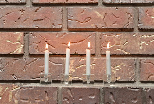 Closeup of lit candles on a brick fireplace mantle.