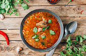 Traditional Georgian tomato soup Kharcho with beef and rice on rustic wooden background.