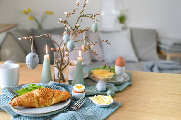 istock Breakfast table with boiled egg, croissant and pastel turquoise Easter decoration in a small living room, copy space, selected focus 1471751798