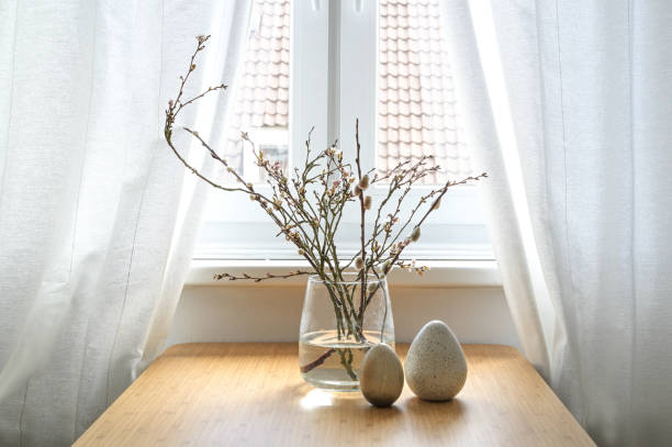 istock Pussy willow catkins and flowering branches in a glass vase and artificial eggs as Easter decoration on a table at the window in an old town city flat, copy space, selected focus 1471751821