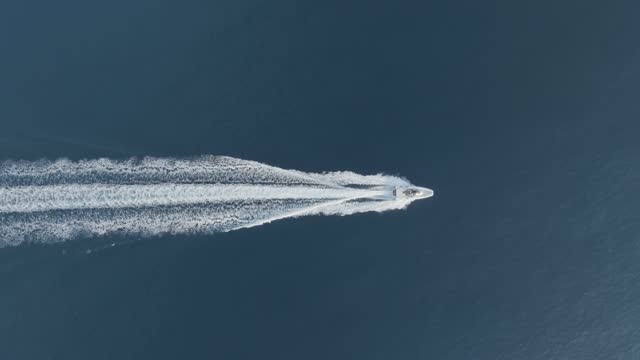 Aerial view of a speedboat sailing along the coast, Sicily, Italy.