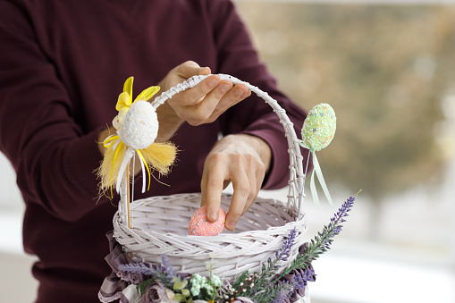 Easter toys. Easter basket with a decorative rabbit in the hands of a man. Blurred background, copy space.