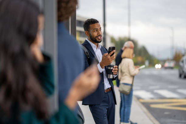 istock Businessman talking on mobile phone videocall while waiting for bus 1471760978