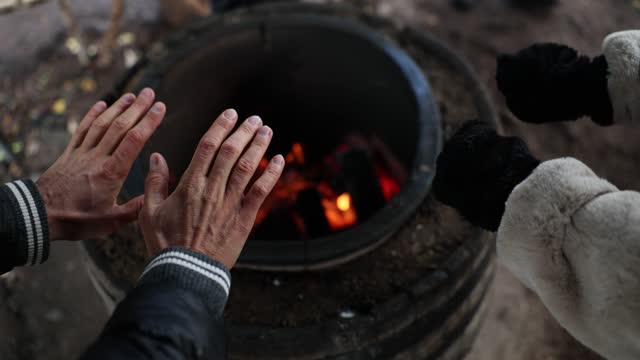 Homeless people warm hands by fire closeup