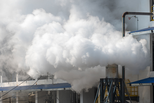 Factory isolated on white with smoke billowing from the smoke stacks.Could be useful in a environmental composition.This is a detailed 3d rendering.