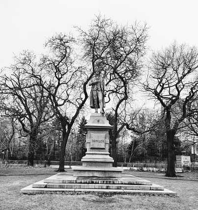 Johann Christoph Friedrich von Schiller Monument by\nErnst Bilhauer Rau in 1886. Located in the \nLincoln Park Conservatory Garden. \n\nIn black and white, front view of the Schiller Monument framed by bare trees. Picture taken on a cold morning in Chicago February 2023.