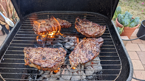 A snapshot of four sirloin steaks being cooked in the backyard.