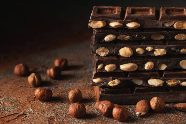 istock Dark and milk chocolate with nuts on a dark background sprinkled with cocoa powder. 1471773337