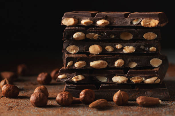 istock Dark and milk chocolate with nuts on a dark background sprinkled with cocoa powder. 1471773338