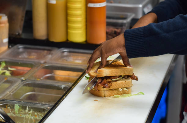 istock Restaurant kitchen employee cutting sandwich in half 1471773901