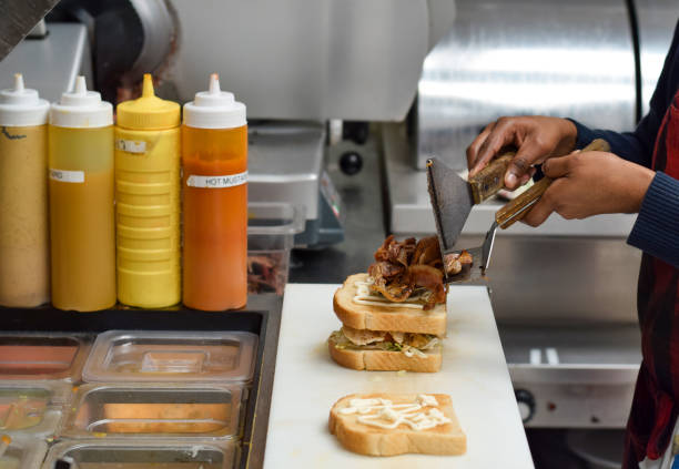 Restaurant kitchen employee preparing Club sandwich with bacon