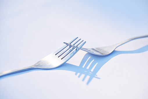 Dinner, shadow and forks on a table for partnership, teamwork and collaboration on a blue studio background. Creative, design and kitchen utensils with reflection of solidarity and team work