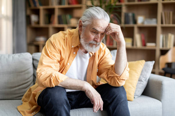 istock Upset old man sitting on couch alone, home interior 1471775223
