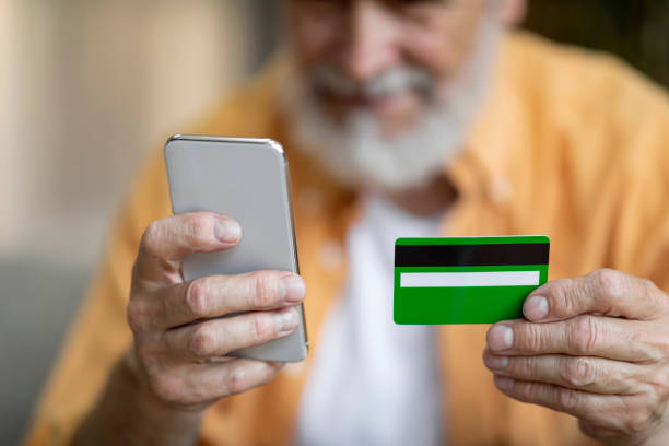 istock Unrecognizable senior man using smartphone and credit card at home 1471775235