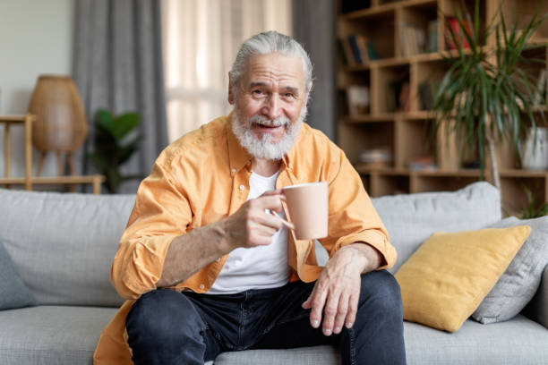homem idoso bebendo café e sorrindo, interior da casa - quilt 60s 70s activity - fotografias e filmes do acervo