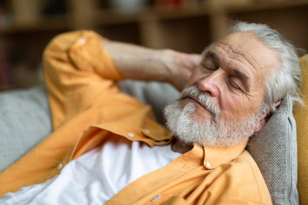 closeup of sleeping senior man, resting on sofa at home - quilt 60s 70s activity imagens e fotografias de stock