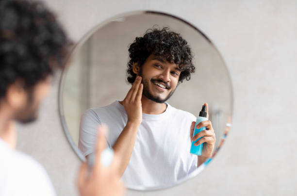 istock Handsome indian man applying moisturizing lotion and touching beard, smoothing after shaving in bathroom 1471775445