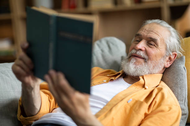 istock Relaxed grandfather chilling on couch, reading book 1471775526