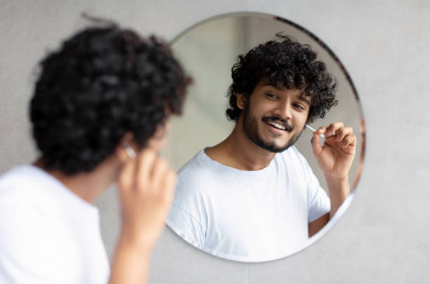 istock Daily hygiene routine. Indian man cleaning ears using cotton swab while doing morning beauty routine in bathroom 1471775785