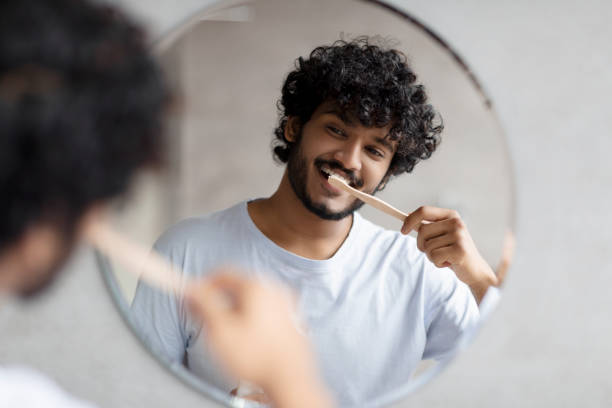 istock Toothcare routine concept. Young indian guy cleaning teeth in the morning using toothbrush and toothpaste 1471775792