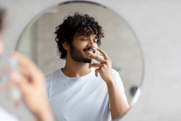 istock Satisfied indian man smelling perfume, doing morning beauty routine, enjoying pleasant odor, standing in bathroom 1471775822