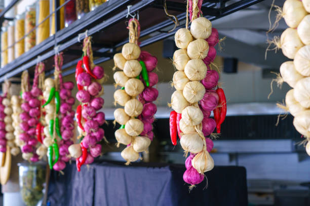 ajo, cebolla y chile, producto de temporada otoñal, colgado en troncos de madera en la cocina - garlic hanging string vegetable fotografías e imágenes de stock
