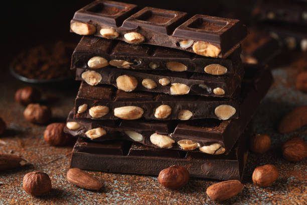 istock Dark and milk chocolate with nuts on a dark background sprinkled with cocoa powder. 1471778535