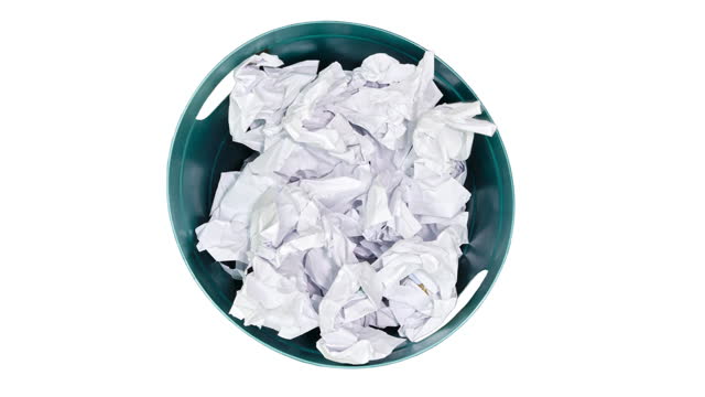 Plastic trash can being filled with crumpled sheets of white paper, isolated on a white background