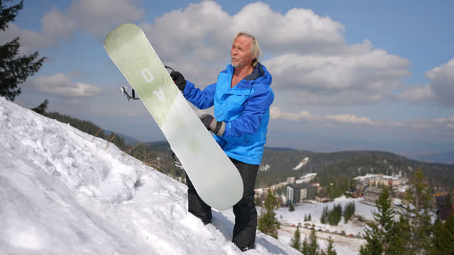 SLO MO Senior man with snowboard enjoying a beautiful day
