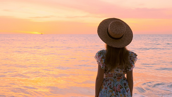 Slow motion of a female tourist standing at a stunning beach in Thailand. A peaceful moment during the holiday season. Summer tropical sea vacation.