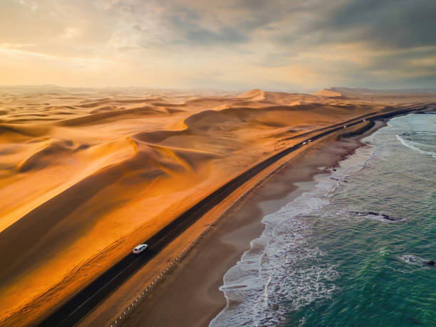Aerial top view of street road with Namib Desert Safari, sand dune, coast sea in Namibia, South Africa. Natural landscape background at sunset. Famous tourist attraction. Sand in Grand Canyon stock photo