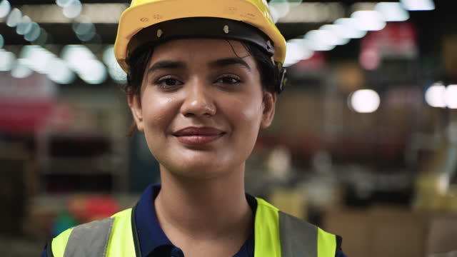 Closeup of happy female worker standing smiling in workplace at factory.