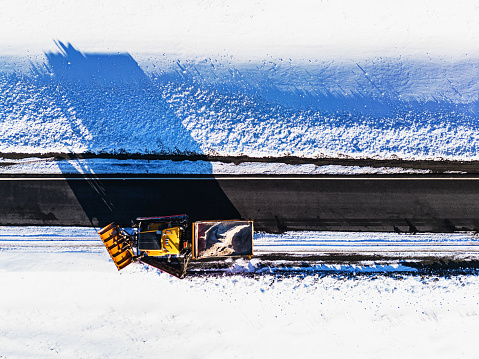 A snowplow operator clears the edge of a highway on-ramp.